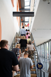 Eine Gruppe Menschen laufen über eine Treppe in den 1. Stock des Museums