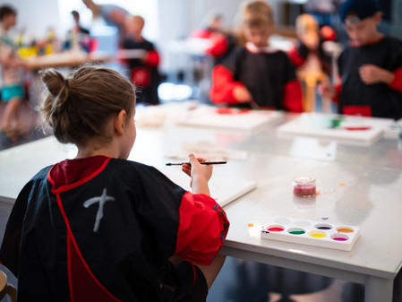 Kinder sitzen an einem Tisch und malen